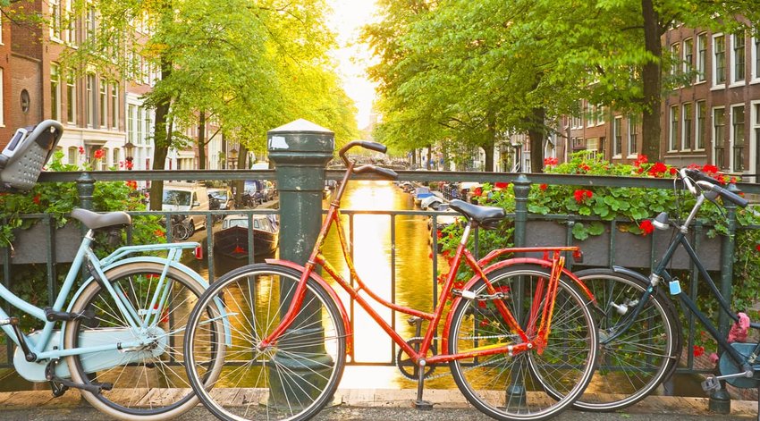 bikes leaning against railing on canal in amsterdam