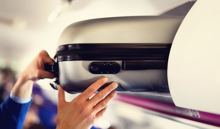 Hand-luggage compartment with suitcases in airplane.