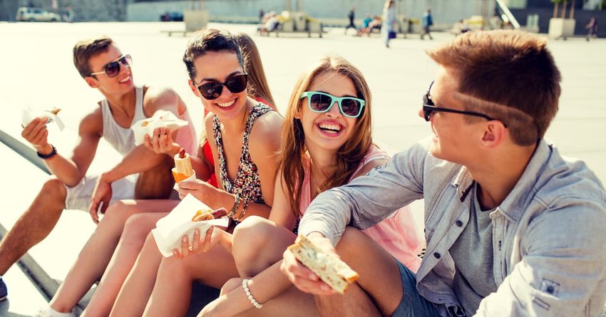 Group of smiling friends sitting on city square