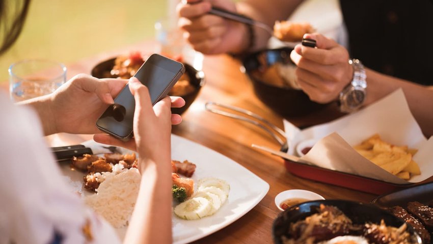 Woman mobile while dining with friends in restaurant