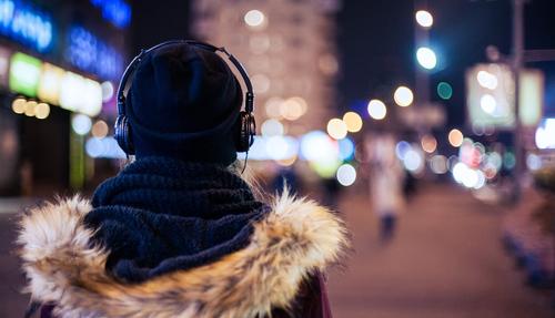 Girl walking through night city street listening to the music 