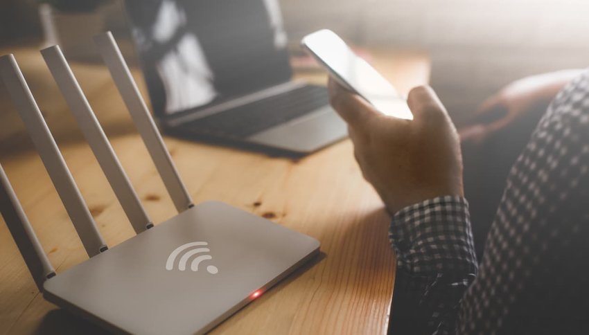 image of wireless router and a man using smartphone on living room