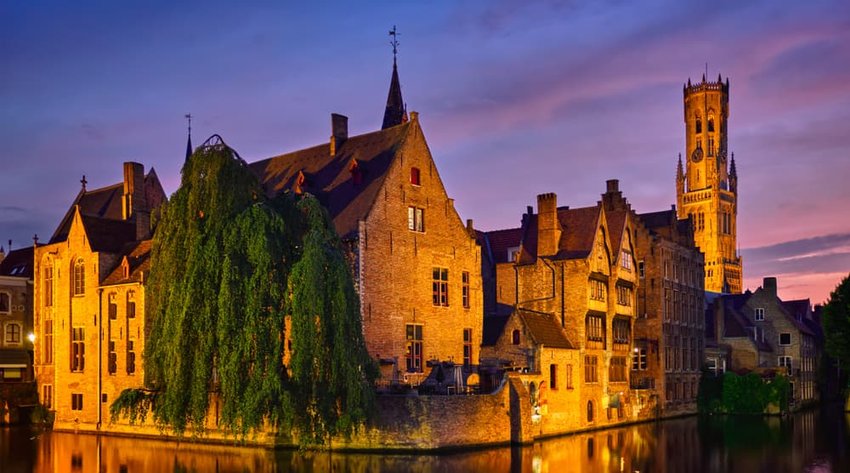 Rozenhoedkaai canal with Belfry and old houses along canal with tree in the night. Brugge, Belgium