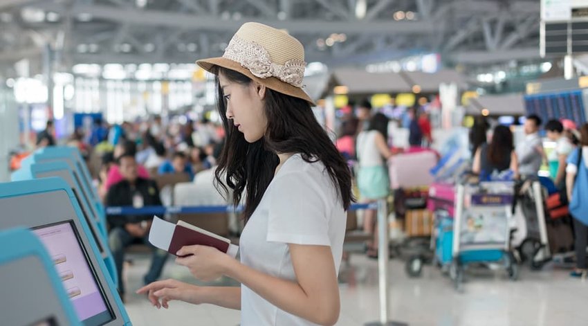 Young woman using self check-in kiosks in airport