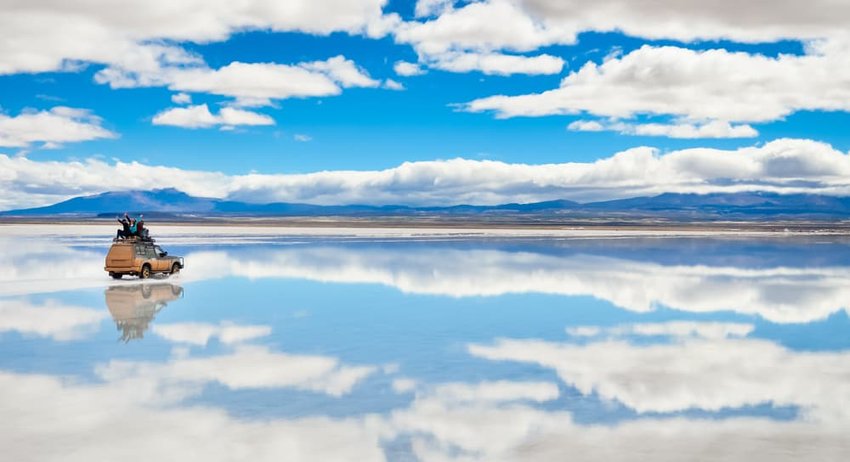 Car driving on the mirror surface of Salar de Uyuni in Bolivia.