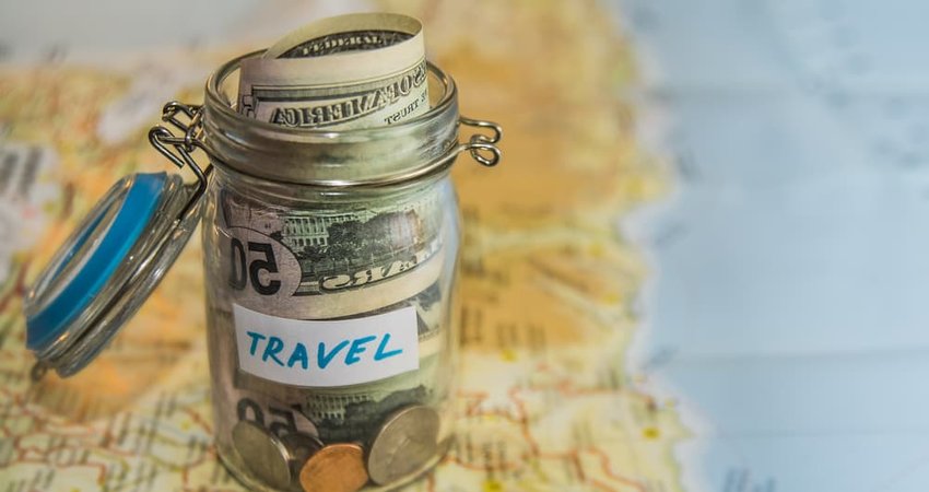 vacation money savings in a glass jar on world map