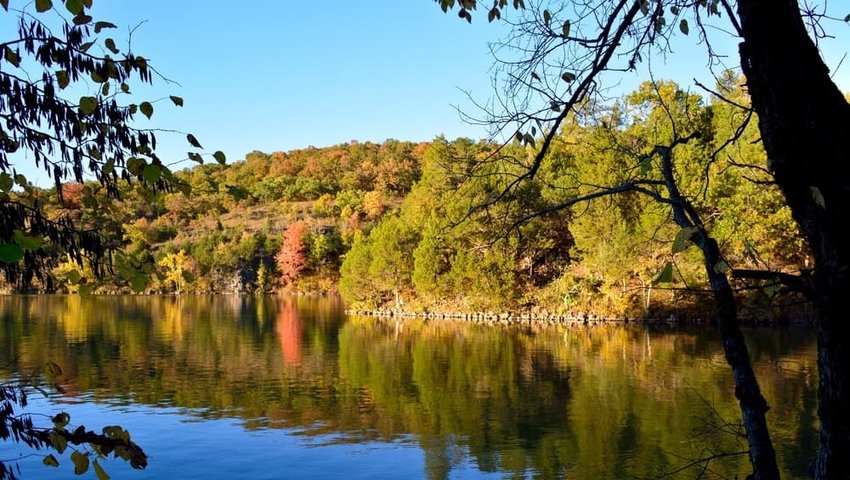 The autumn forest is reflected on the water. Lake of the Ozarks, Missouri