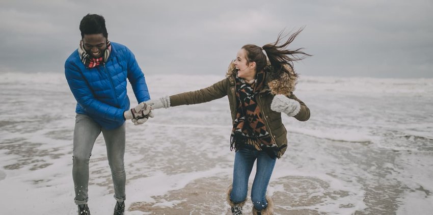 Young Couple Laughing In The Winter Beach Sea