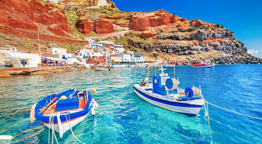 beautiful landscape of two fishing boats anchored to quay at the old port panorama in Oia Ia village on Santorini Greek island in Aegean sea