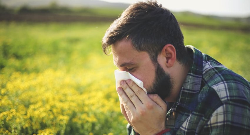 man in field sneezing