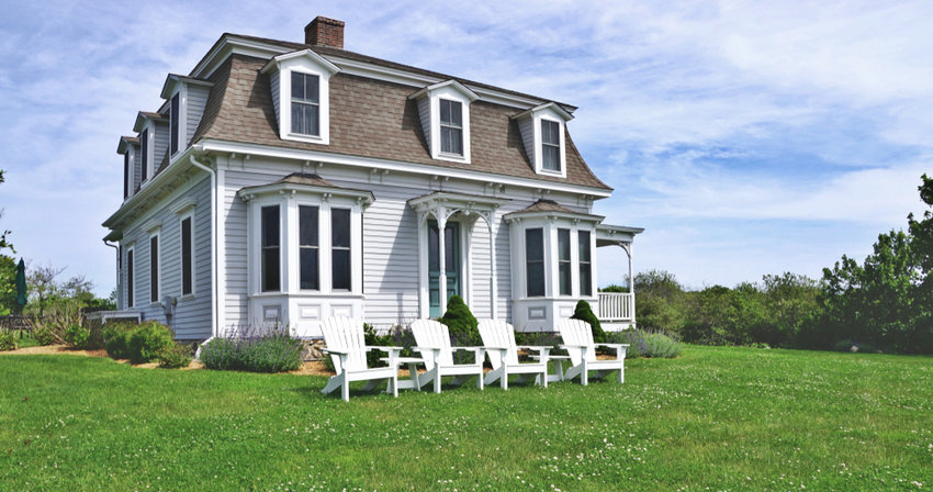 A horizontal image of a classic beach house, with a Mansard roof, on windswept Block Island.