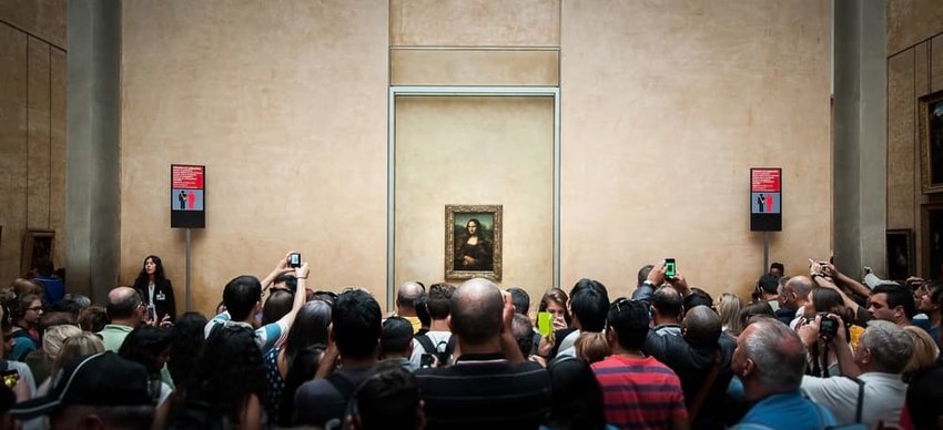 crowds gather in front of the mona lisa at the lourve in paris