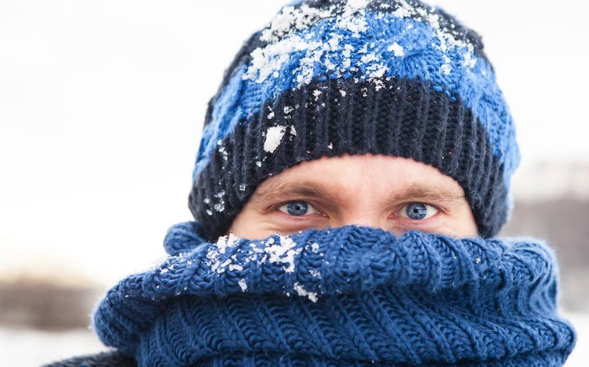 a young man in a hat and a scarf outdoors in winter day