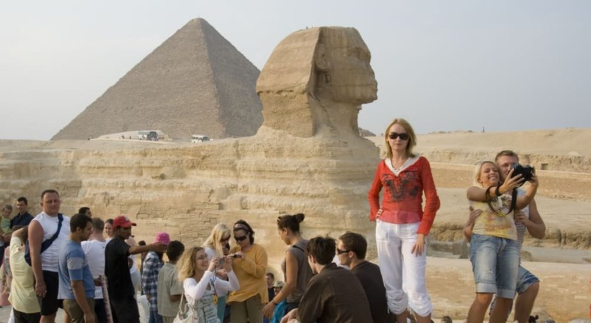 Many joyful tourists are photographed near the pyramids and the Sphinx in Egypt