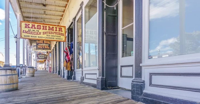 Street scene of a wooden boardwalk and vintage signage of retail establishments in historic Virginia City.