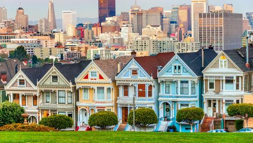 Row of Painted Ladies houses with skyline in background.