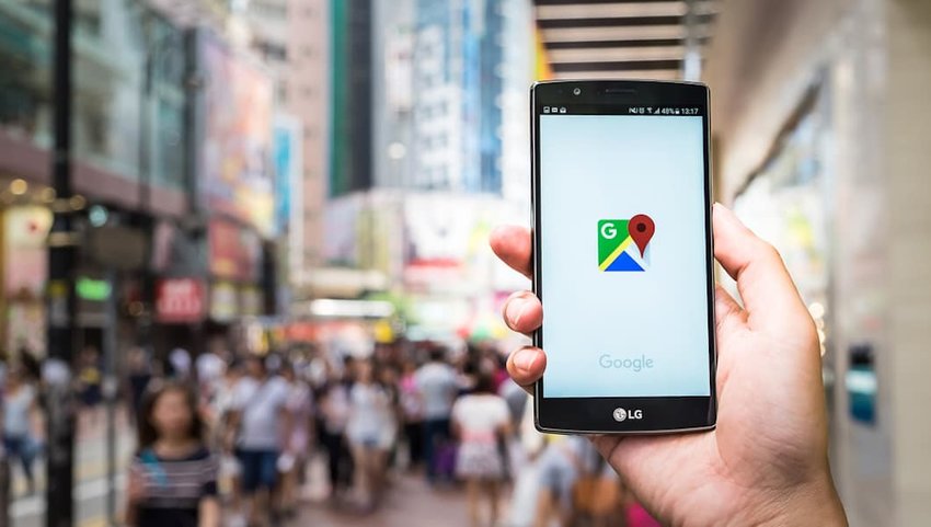 Photo of the Google Maps logo on a phone with a cityscape in the background