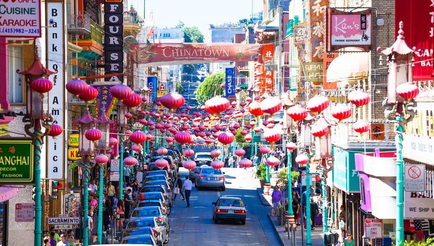 View of the main street of he chinatown district, traffic of cars and people.