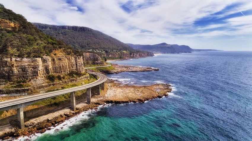 Photo of an elevated road, between mountains and the ocean