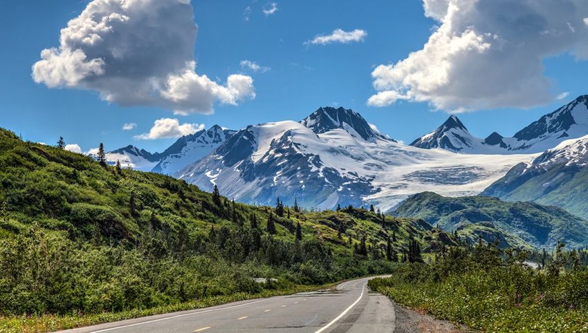 Photo of a road leading to towering mountains