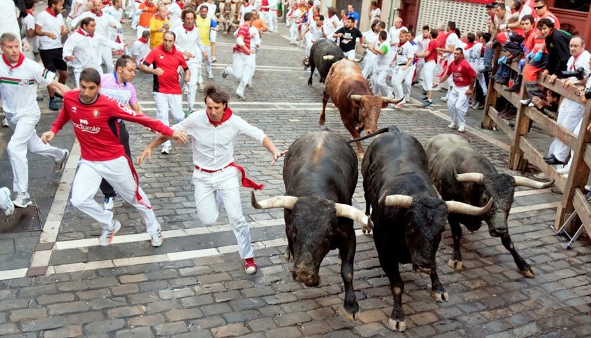 men run from bulls in street Estafeta during San Fermin festival in Pamplona