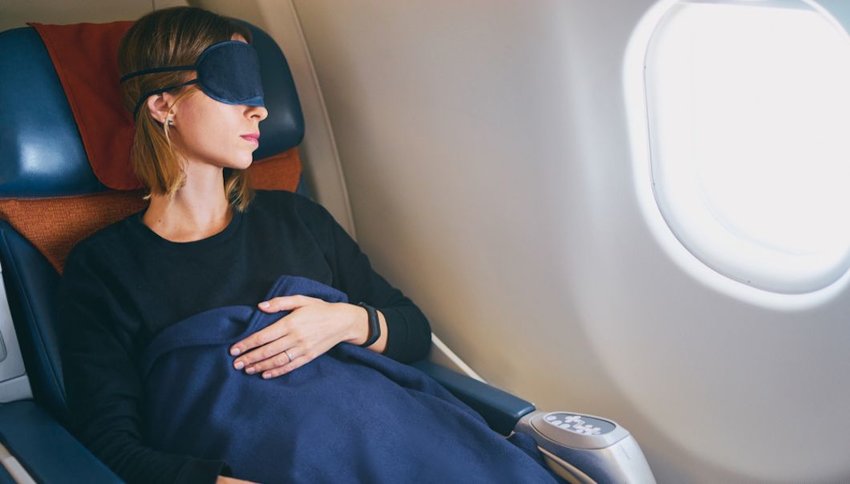 Woman sleeping on plane with eye mask