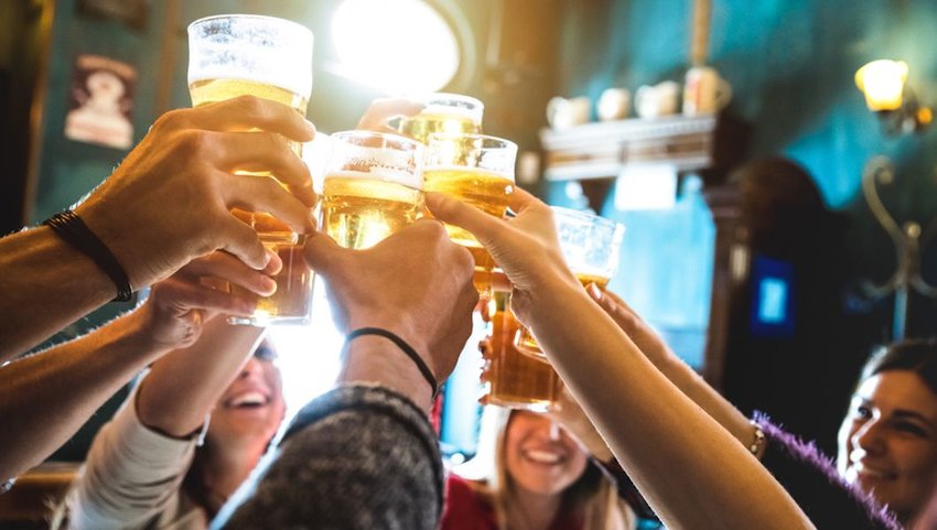 Group of happy friends drinking and toasting beer at brewery bar restaurant.