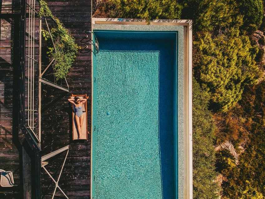 Aerial photo of hotel pool with a woman on a lounge next to the water