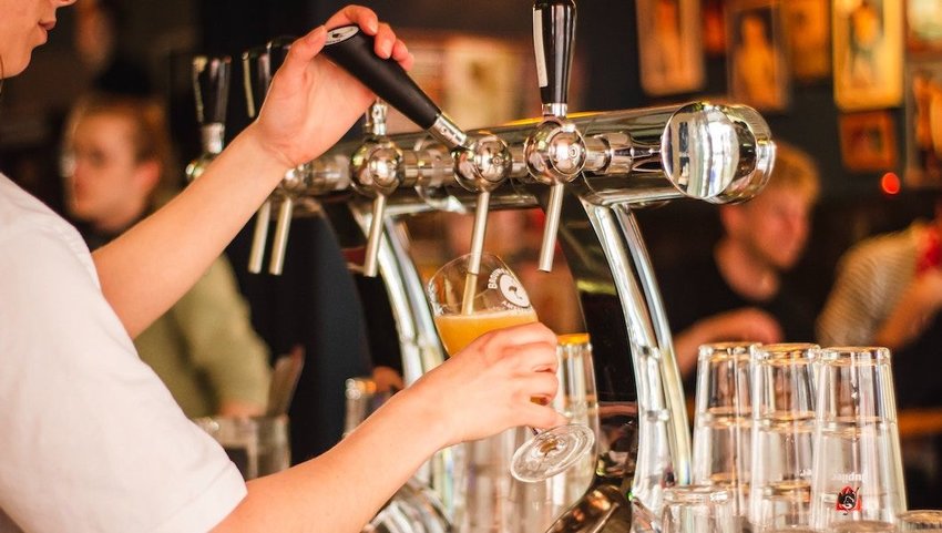 Bartender pouring a glass of beer at a bar.