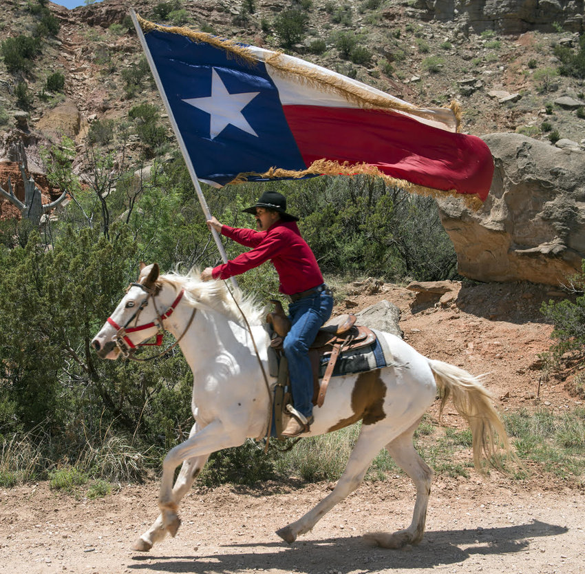 Photo of man on horseback holding a Texas state flag