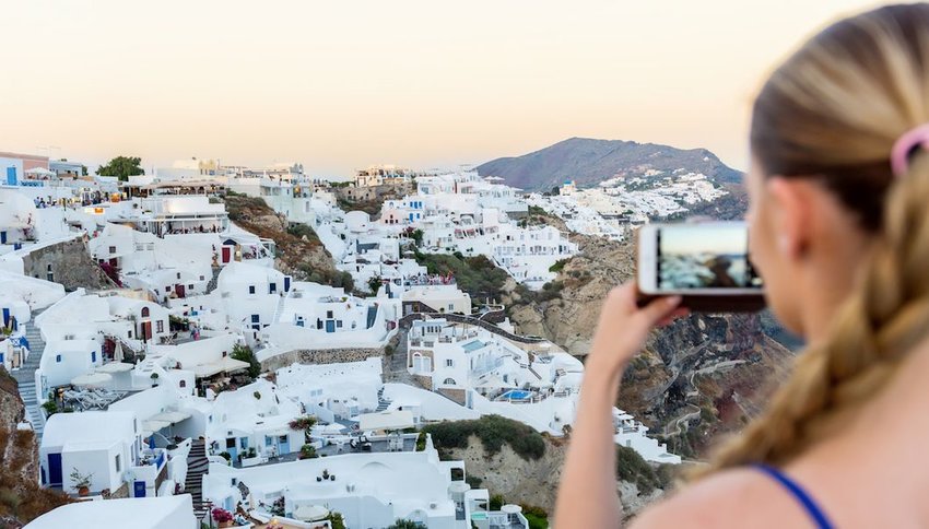 Female tourist capturing photo of Oia, Santorini