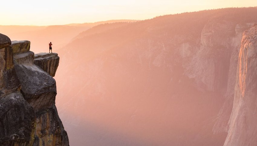 hiker stands at the edge of a cliff at Taft Point