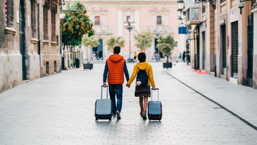 Traveling couple walking through street with luggage