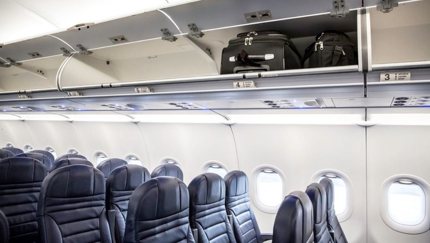 Side view of empty airplane interior with bags in the overhead luggage compartments