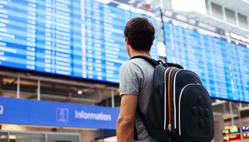 man waiting near airport flight timetable