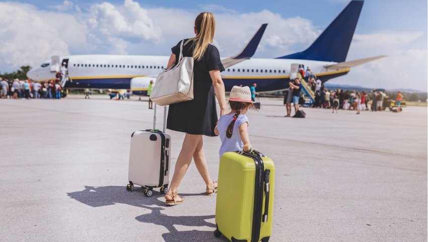 Mother and daughter boarding plane with large carry-on luggage