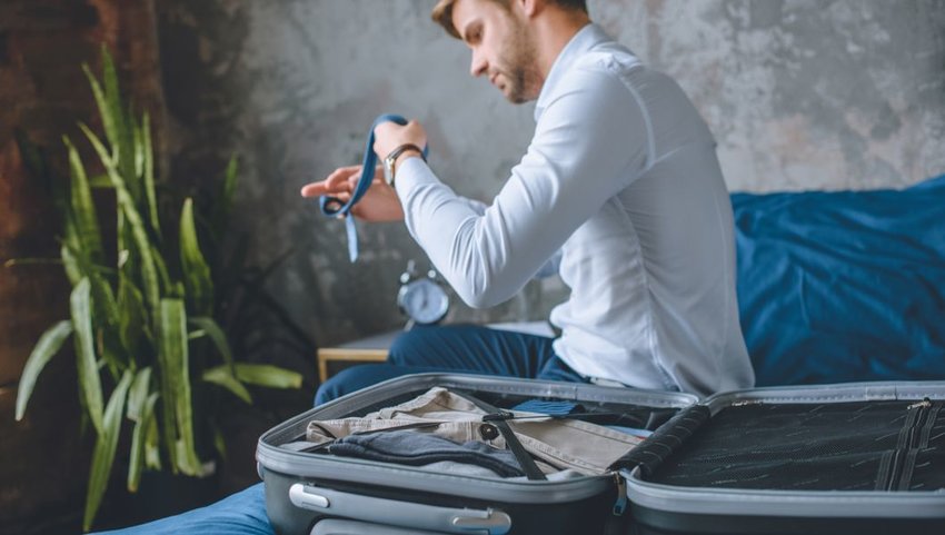 Businessman carefully packing suitcase in hotel room
