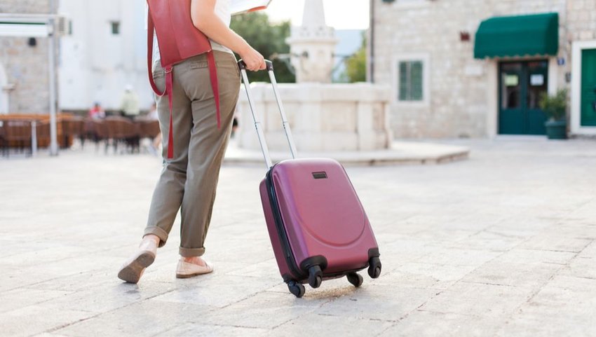 Female traveler carrying luggage through the streets of Italy