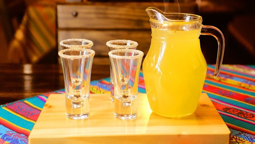 A pitcher of Canelazo, a hot cider drink, on a table with glasses