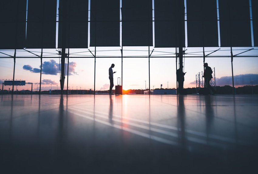 Man standing in airport with the sun setting in the background.