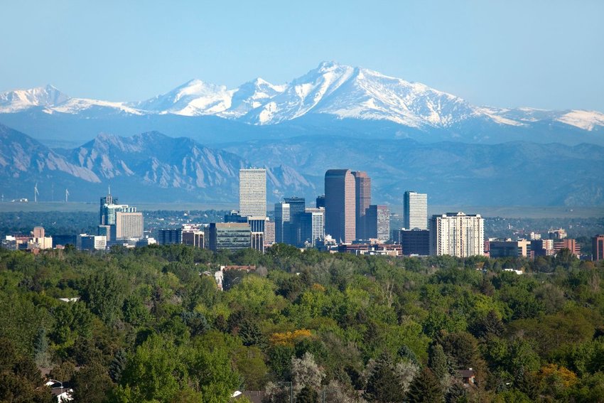 View of Denver, Colorado surrounded by trees with mountains in background 