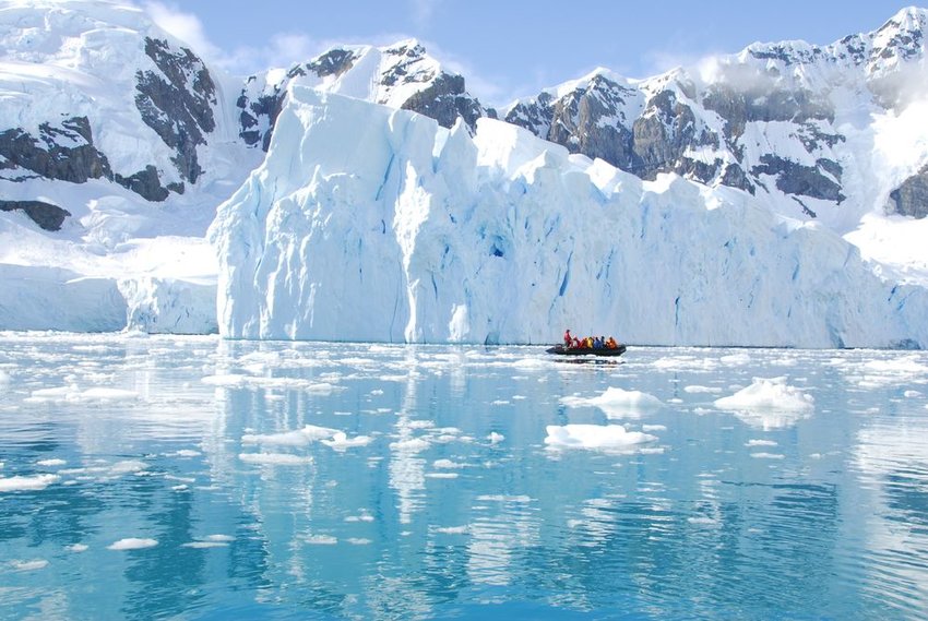 People in a boat next to an iceberg