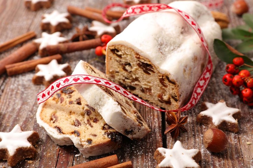 Loaf of Stollen on wood table, surrounded by Christmas cookies