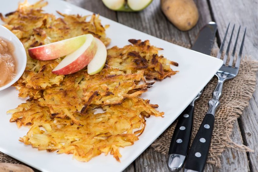 Traditional kartoffelpuffer on a white plate with apple slices and applesauce 