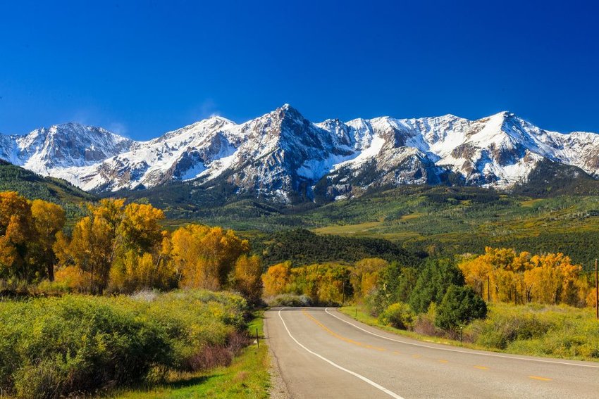 Road to rocky mountains covered in snow in fall