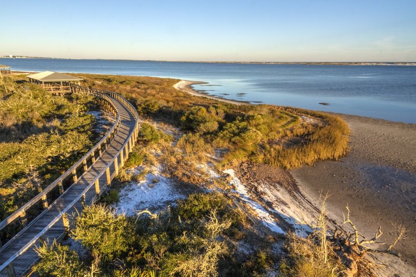 A boardwalk curves over the vegetation on the dunes in Big Lagoon State Park in Florida