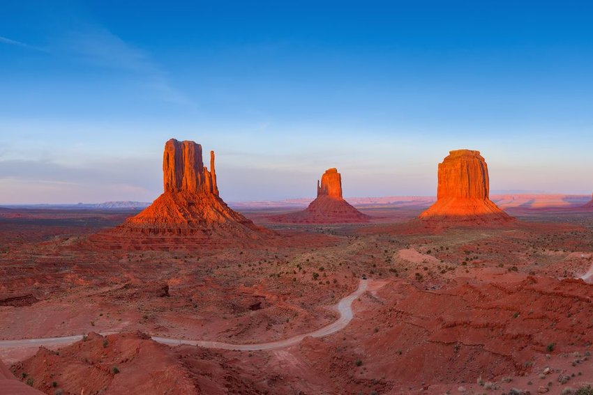 Sunset on Monument Valley, road winding in between 