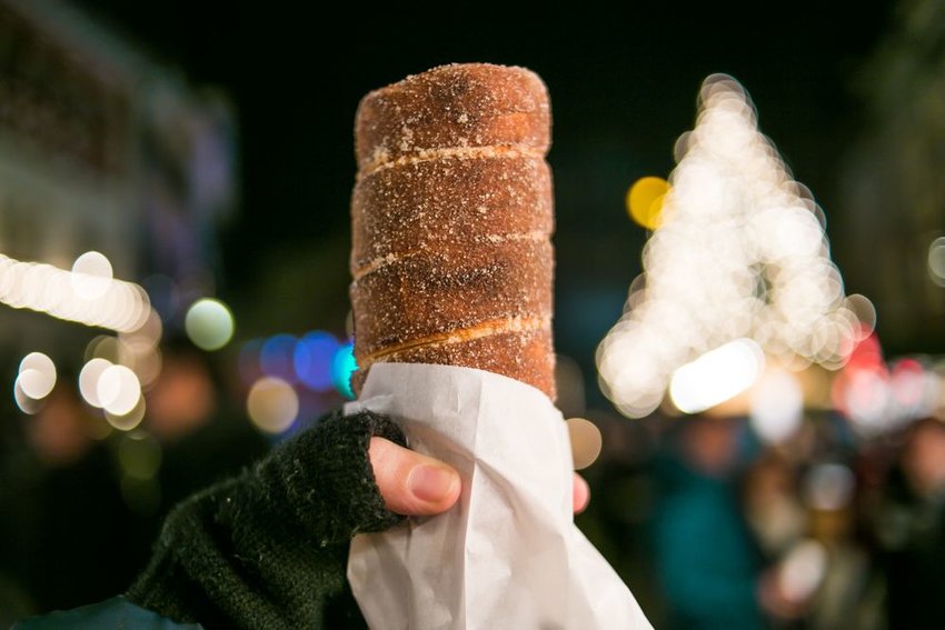 Someone holding chimney cake with Christmas lights in the background 