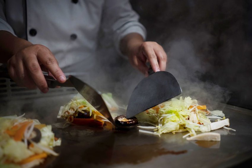 Japanese Teppanyaki chef cooking in an open restaurant kitchen