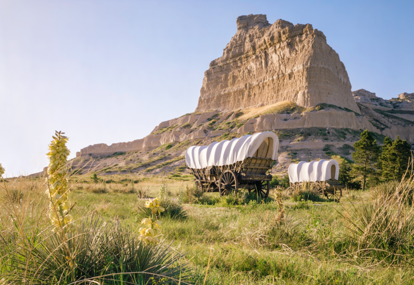 Covered wagons in front of rocky bluff at Scotts Bluff National Monument, Oregon Trail in Nebraska